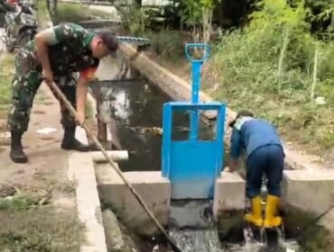 Sertu Hariyono, anggota Koramil 0819/01 Kota bersama Dinas Lingkungan Hidup dan Kebersihan Pemkot (DLHKP) Pasuruan melaksanakan kegiatan pembersihan saluran air