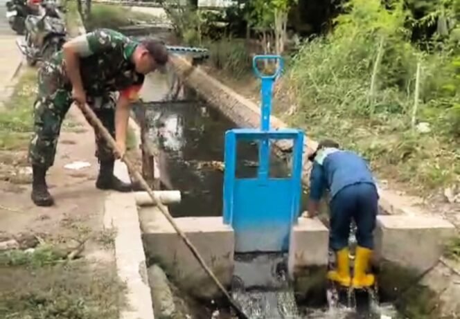 
					Sertu Hariyono, anggota Koramil 0819/01 Kota bersama Dinas Lingkungan Hidup dan Kebersihan Pemkot (DLHKP) Pasuruan melaksanakan kegiatan pembersihan saluran air